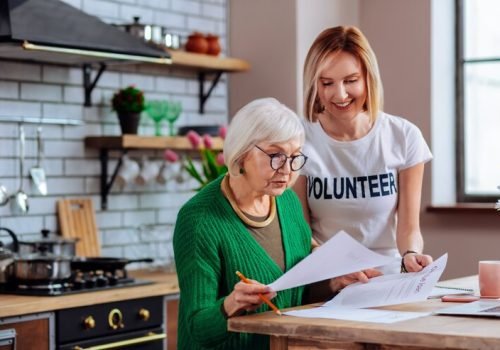 young-adult-volunteer-discussing-with-aging-woman-kitchen_259150-43861